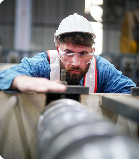 À l'intérieur d'une usine, un ouvrier industriel en action sur une presse à métaux tenant une pièce d'acier prête à être travaillée.