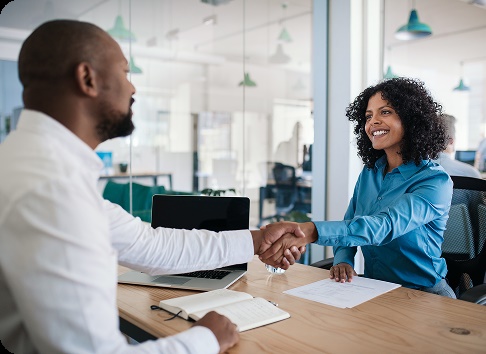 Un manager afro-américain souriant assis à son bureau dans un bureau serrant la main d'un candidat à un emploi après un entretien