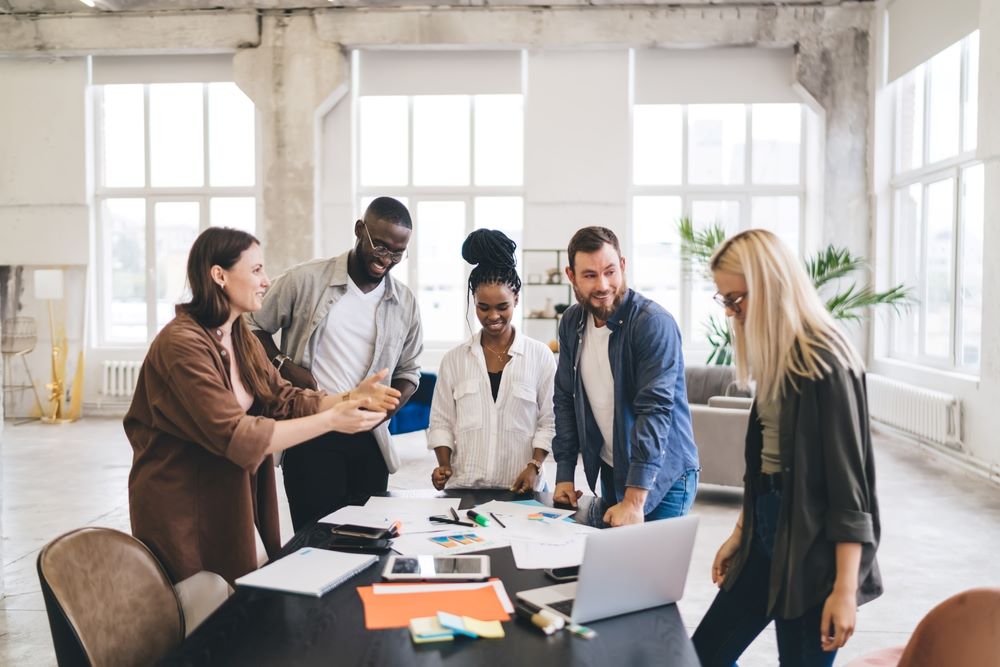 Des architectes masculins et féminins se rassemblent autour d'une table avec des papiers et des gadgets tout en partageant des idées sur le nouveau plan d'entreprise des start-ups