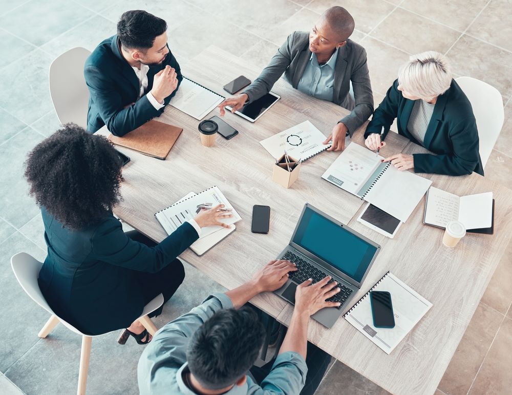 Personnes d'affaires, réunion et papier avec des graphiques pour la planification des ventes, les portfolios et les rapports d'entreprise. Vue de dessus, marketing numérique et équipe avec technologie dans la discussion pour le brainstorming, l'idée ou abonnement de croissance