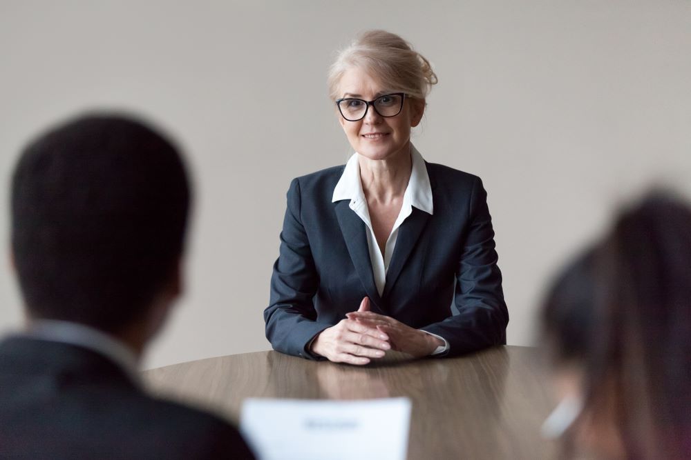 Souriante postulante d'un emploi de niveau supérieur d'âge moyen, écoutant ses questions en faisant la première impression lors de l'entrevue, recruteurs interrogeant un candidat plus âgé, concept de recrutement, d'âge et d'emploi